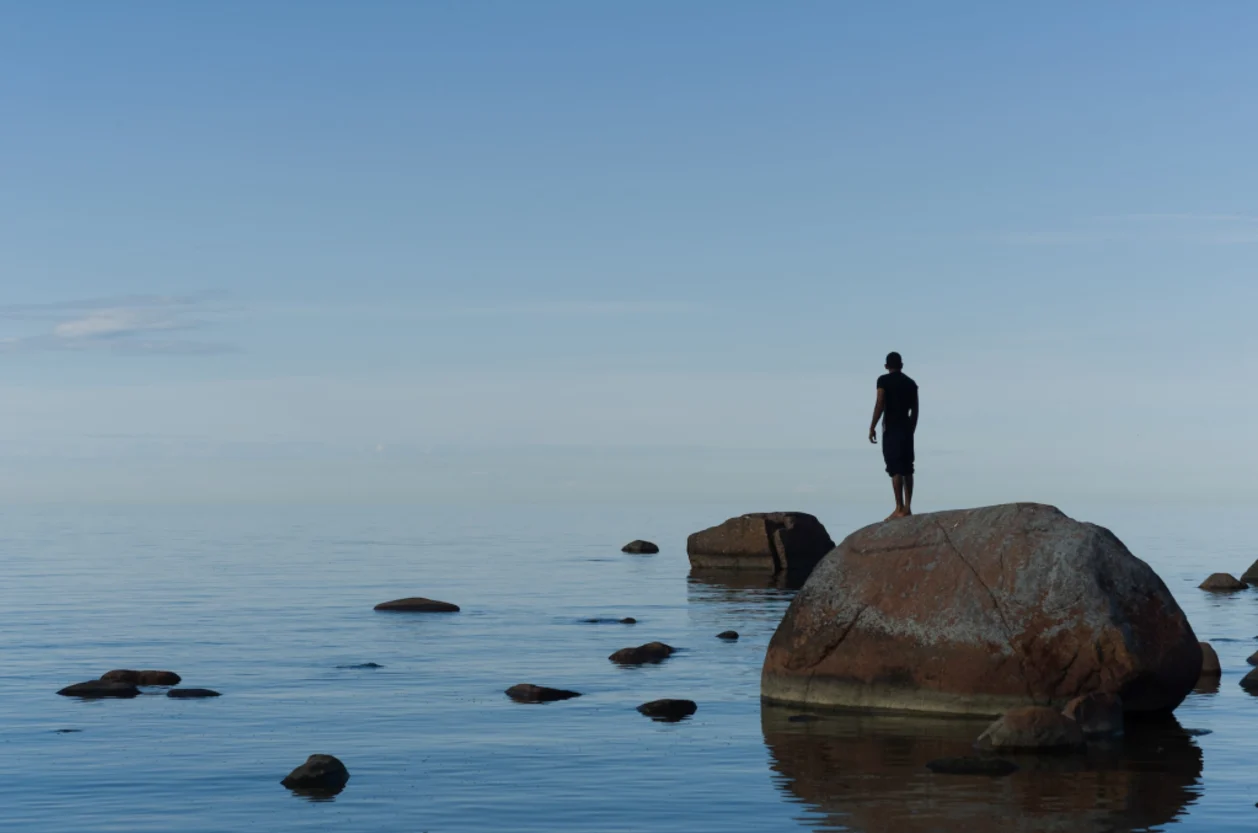 Man standing on rock looking at ocean